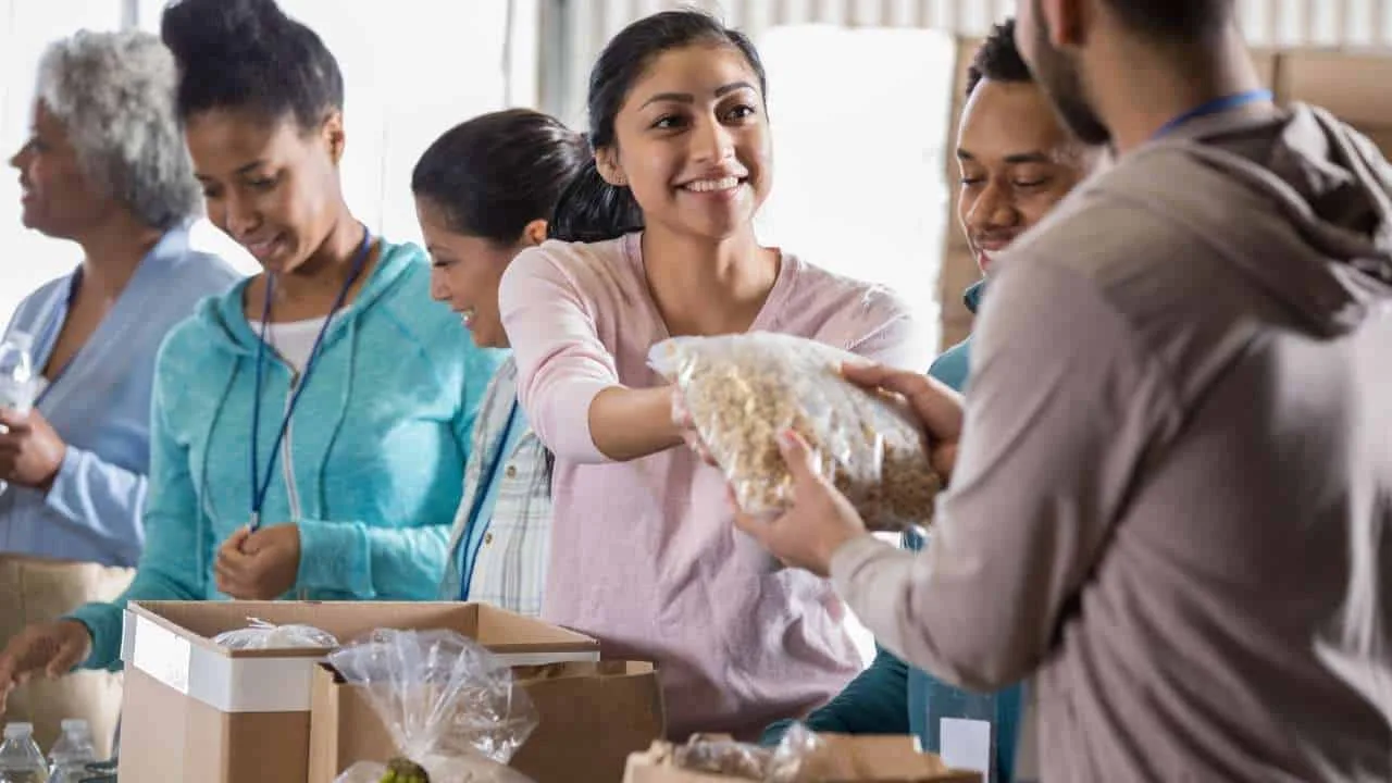 Grupo de voluntarios en un banco de alimentos distribuyendo comida a personas necesitadas.