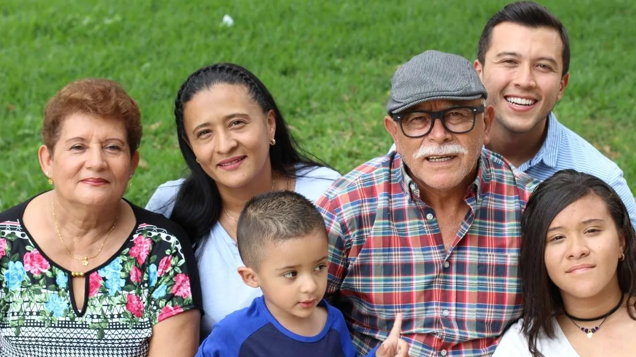 Retrato de seis miembros de una familia sonriendo, incluyendo abuelos, padres y niños.
