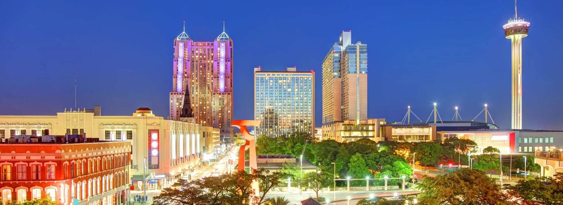 Vista nocturna de edificios y rascacielos en San Antonio, Texas, iluminados por luces de colores.