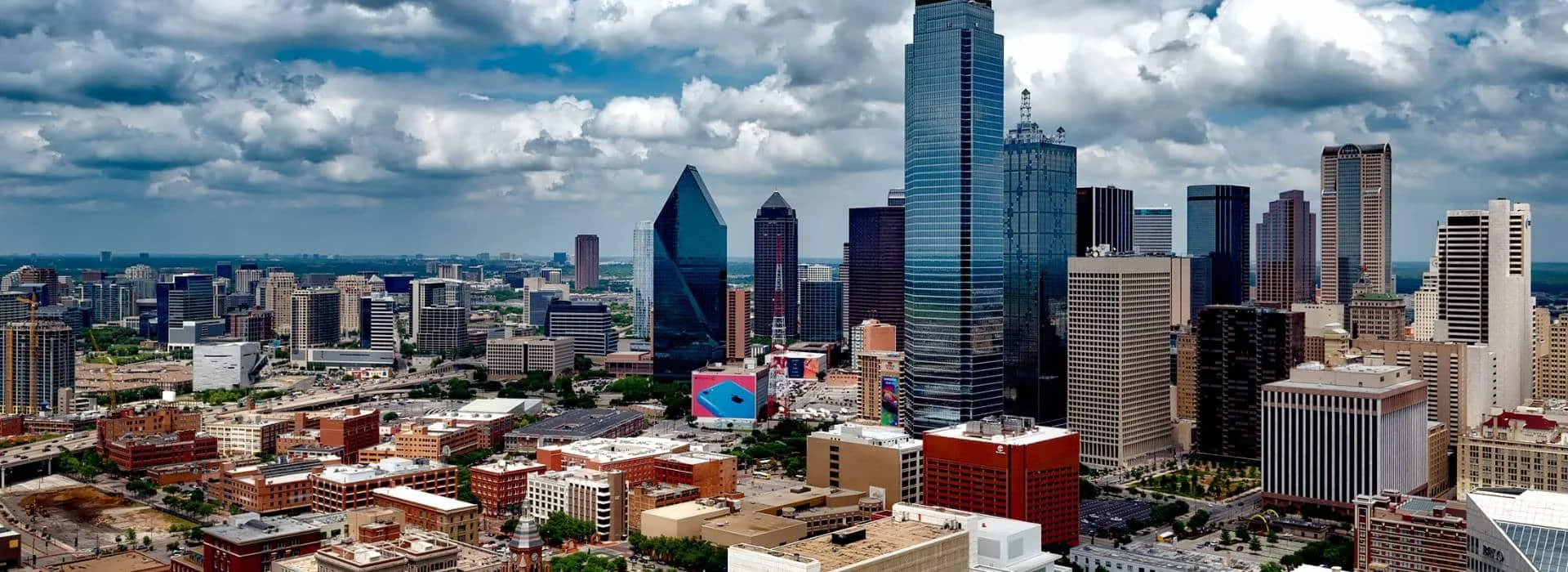 Vista aérea de la ciudad de Dallas, Texas, con edificios modernos y nubes en el cielo.