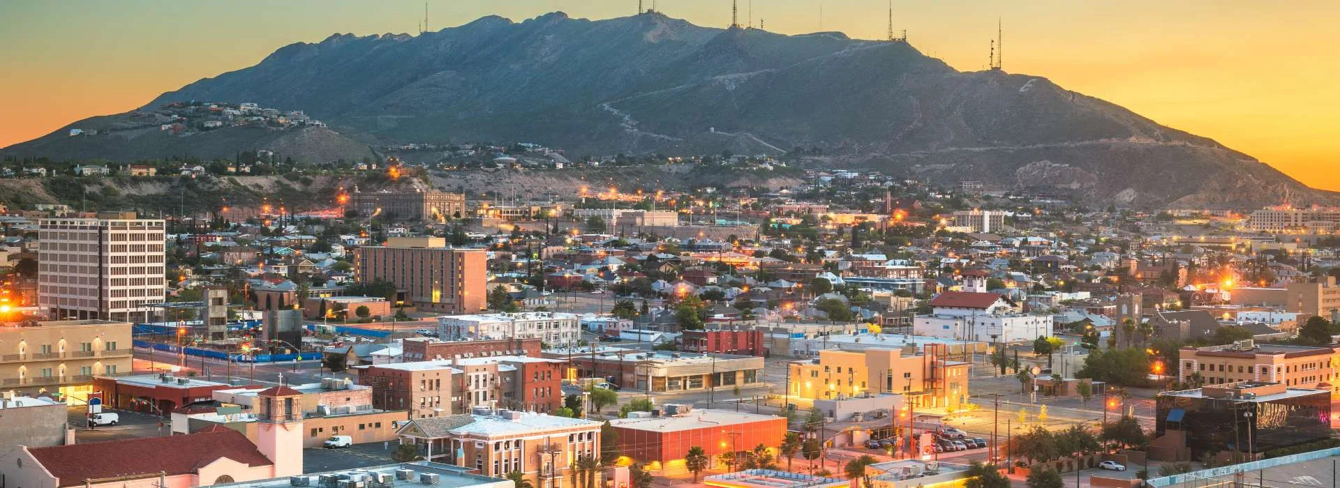 Panorámica de la ciudad de El Paso, Texas, con montañas al fondo y edificios iluminados.