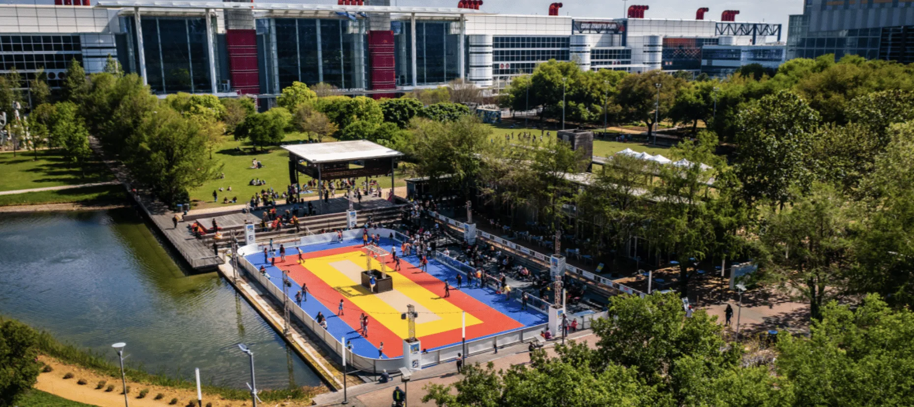 Fuente con chorros de agua en un parque urbano rodeado de árboles y edificios altos.