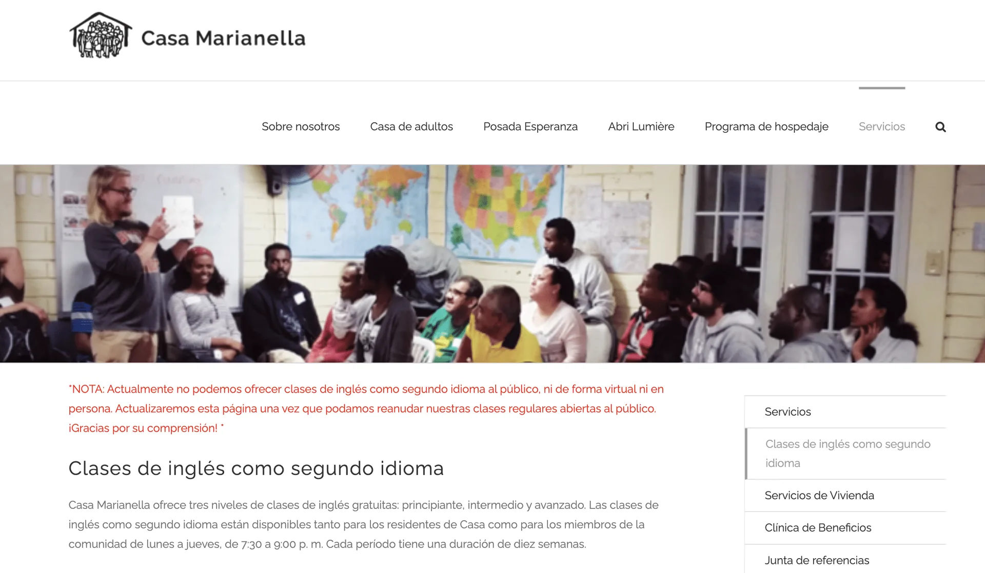 Hombre con casco amarillo y guantes trabajando en una mesa de trabajo en una fábrica.