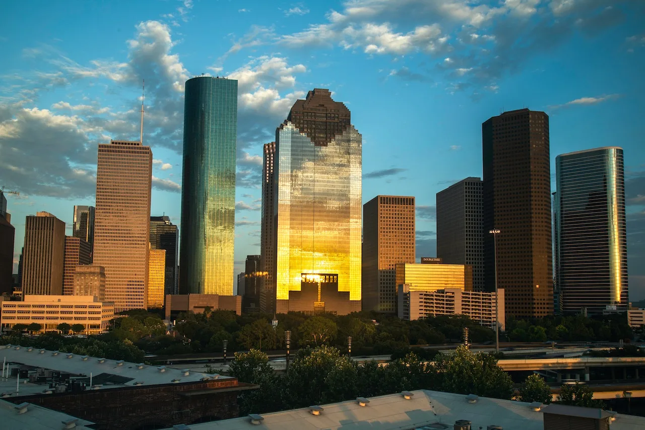 Vista de rascacielos en Houston con reflejos dorados del atardecer en las fachadas de los edificios.