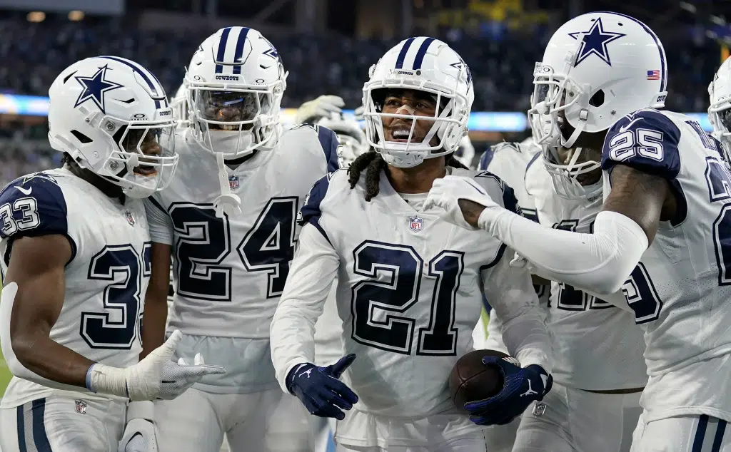 Jugadores de los Dallas Cowboys en uniforme blanco celebrando en el campo de juego.