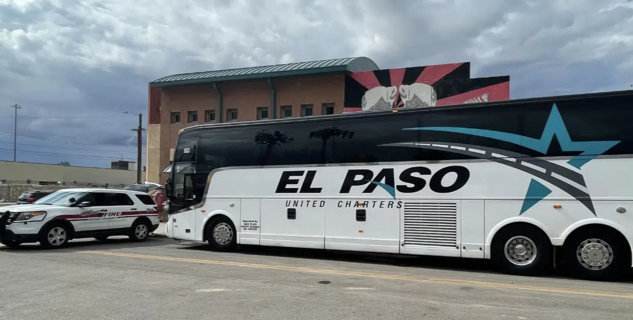 Autobús de pasajeros de El Paso United Charters estacionado junto a un vehículo de emergencia.