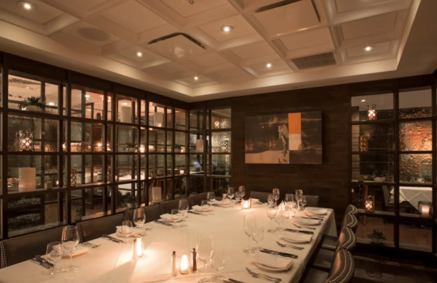 Comedor con mesa larga, sillas elegantes y decoración moderna en un ambiente iluminado suavemente.