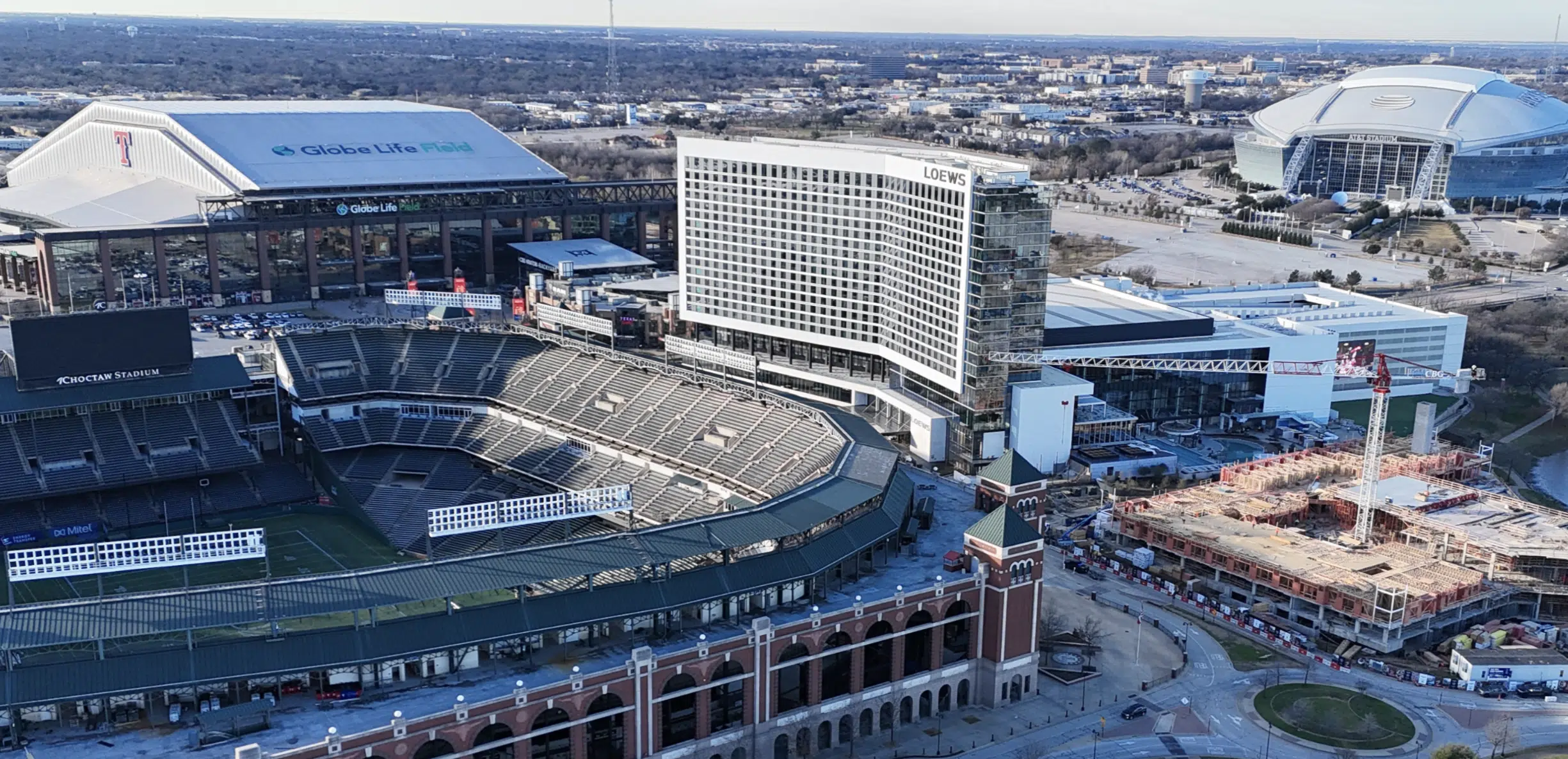 Vista aérea de Globe Life Field, un estadio en Arlington, Texas, con edificios y áreas en construcción alrededor.